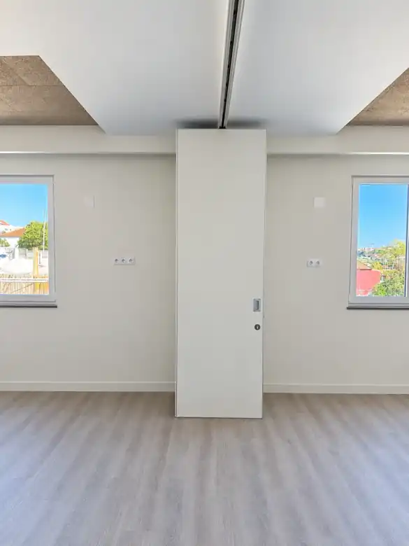 Pormenor da calha superior da parede móvel de harmónio suspensa na Almada International School