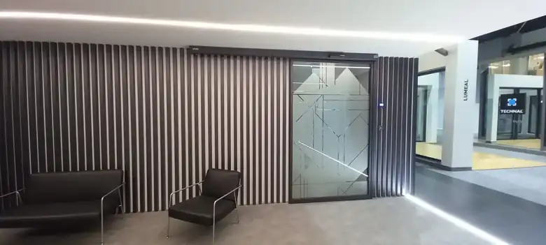 Enquadramento da porta automática da sala de formação com o revestimento de ripas e a zona de espera, na sede da Hydro