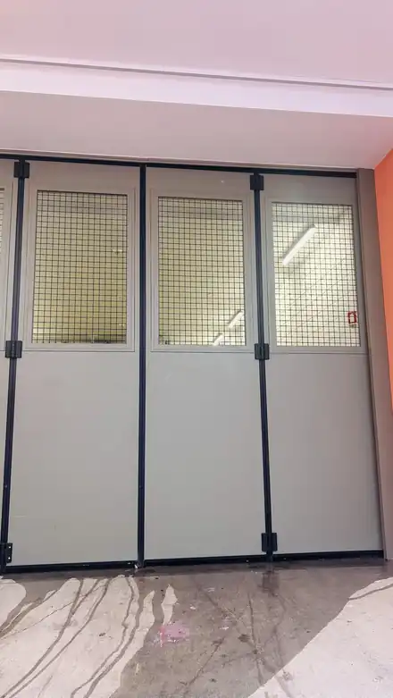 Pormenor da porta de harmónio BREDA Apollo com painel recortado e rede de malha quadrada de 50 mm