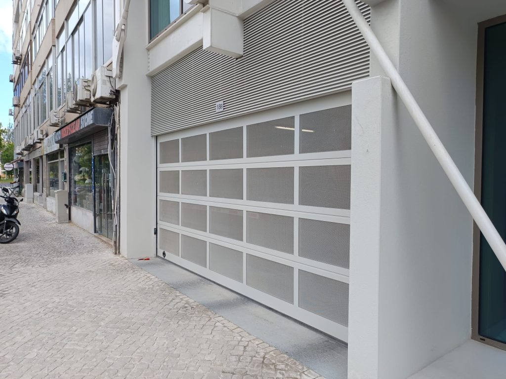 Porta seccionada Oxford Aluline com painel microperfurado numa fachada em Lisboa